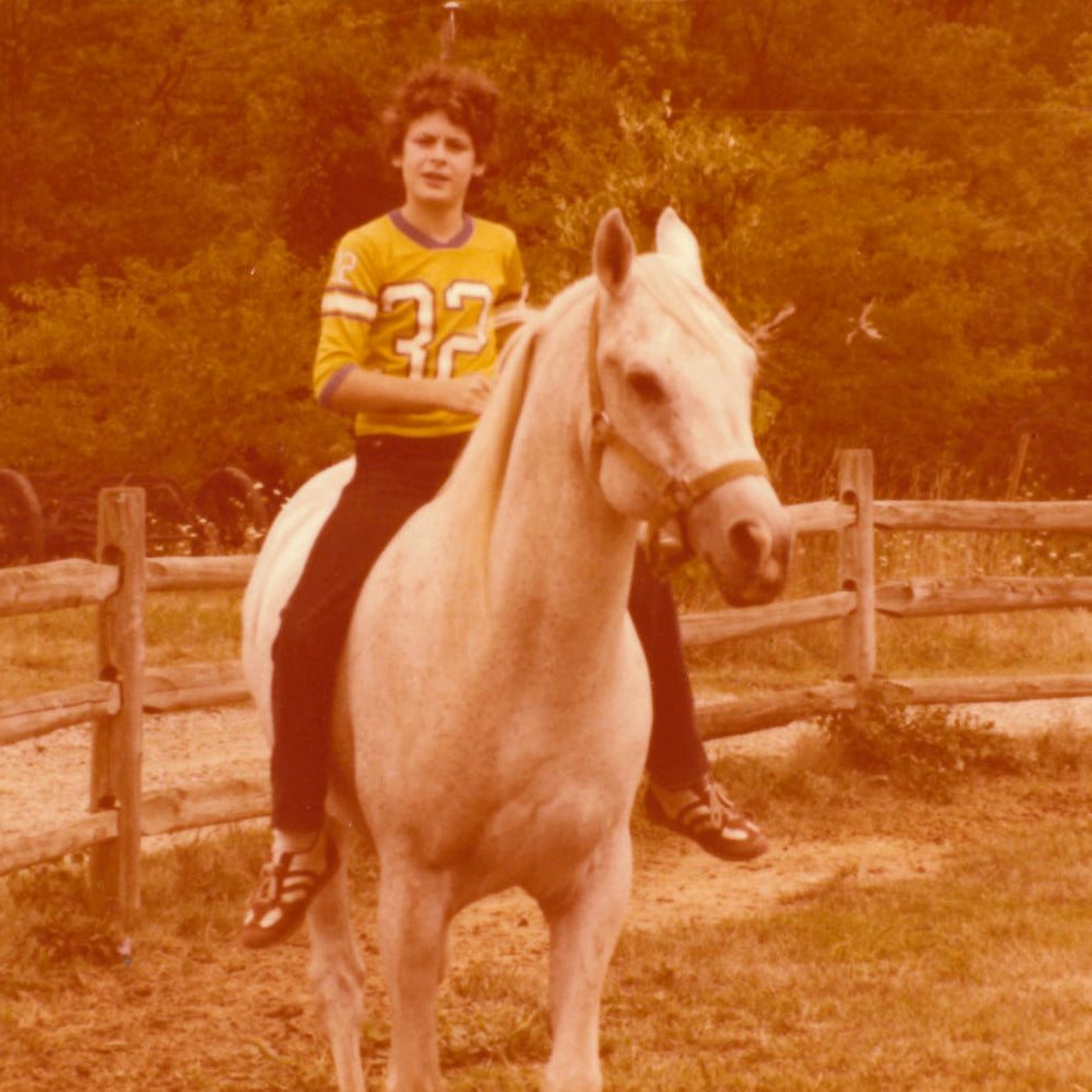 Devon riding his horse Jarey on his family farm with a fence in the background