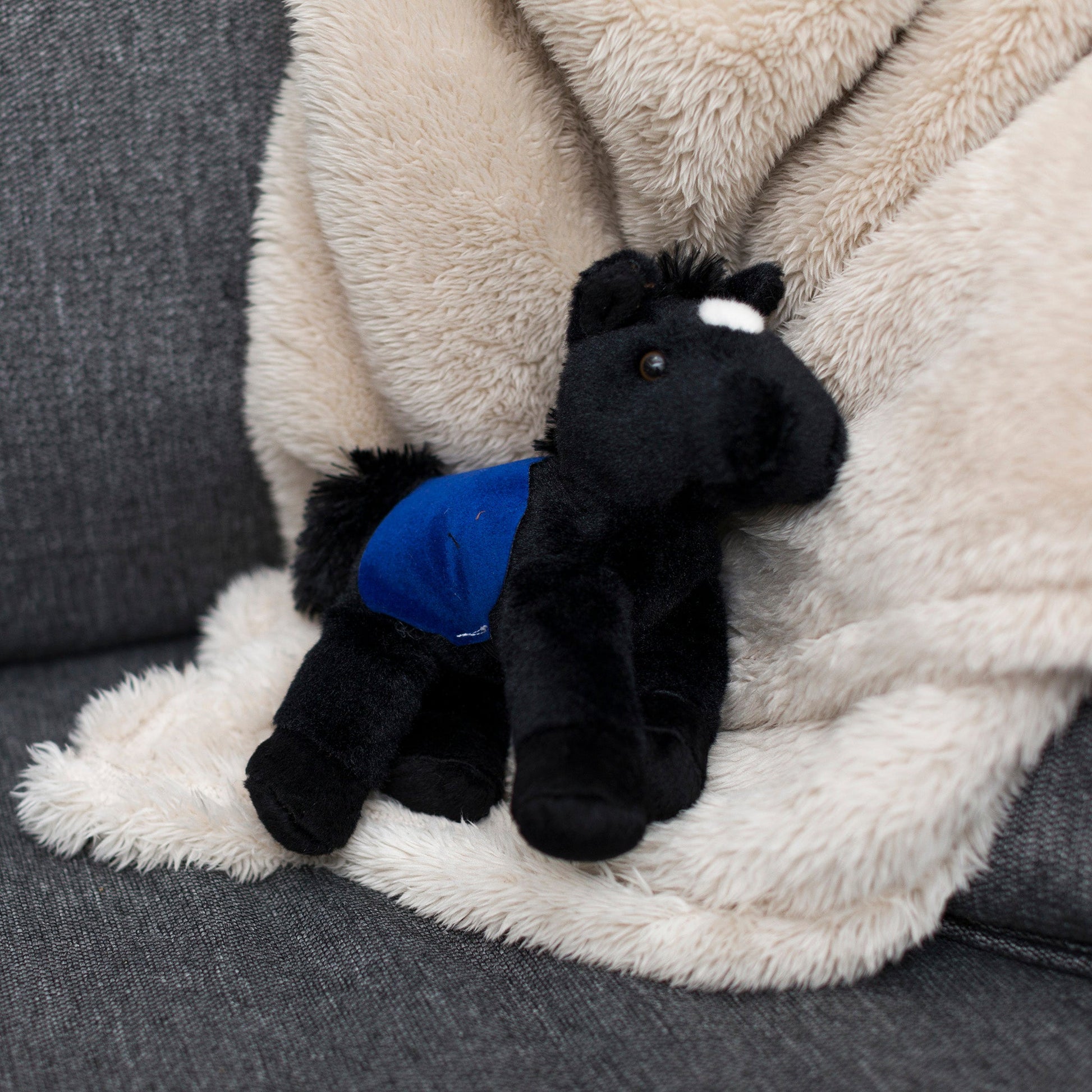 Small Beau Horse horse stuffed animal wearing a royal blue branded mane 'n tail saddle. Standing on the blanket