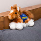 Small orange Clydes horse stuffed animal wearing a royal blue branded mane 'n tail saddle. Standing on cushion