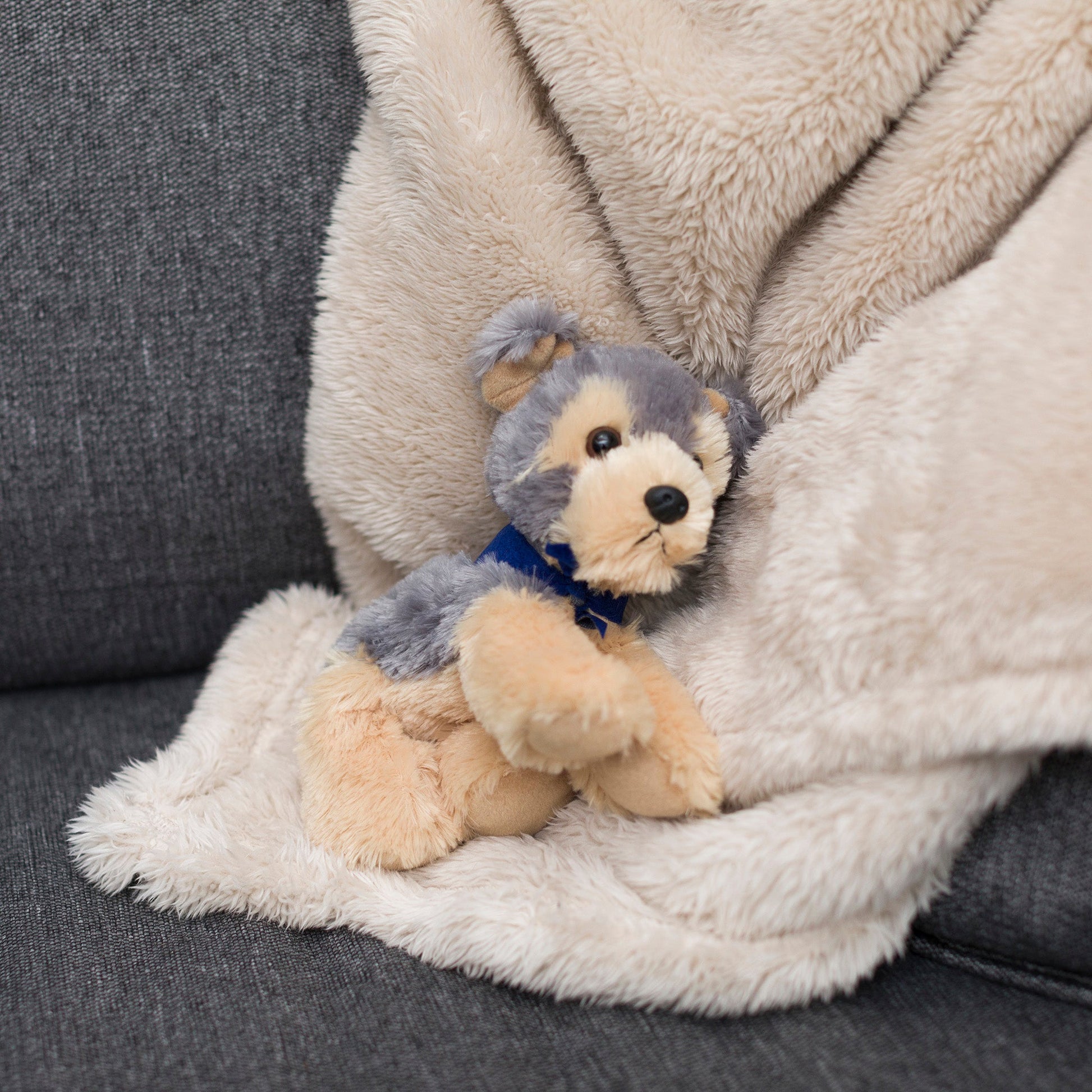 Small Yorkshire Terrier dog stuffed animal wearing a royal blue branded mane 'n tail bandana. Standing on a blanket