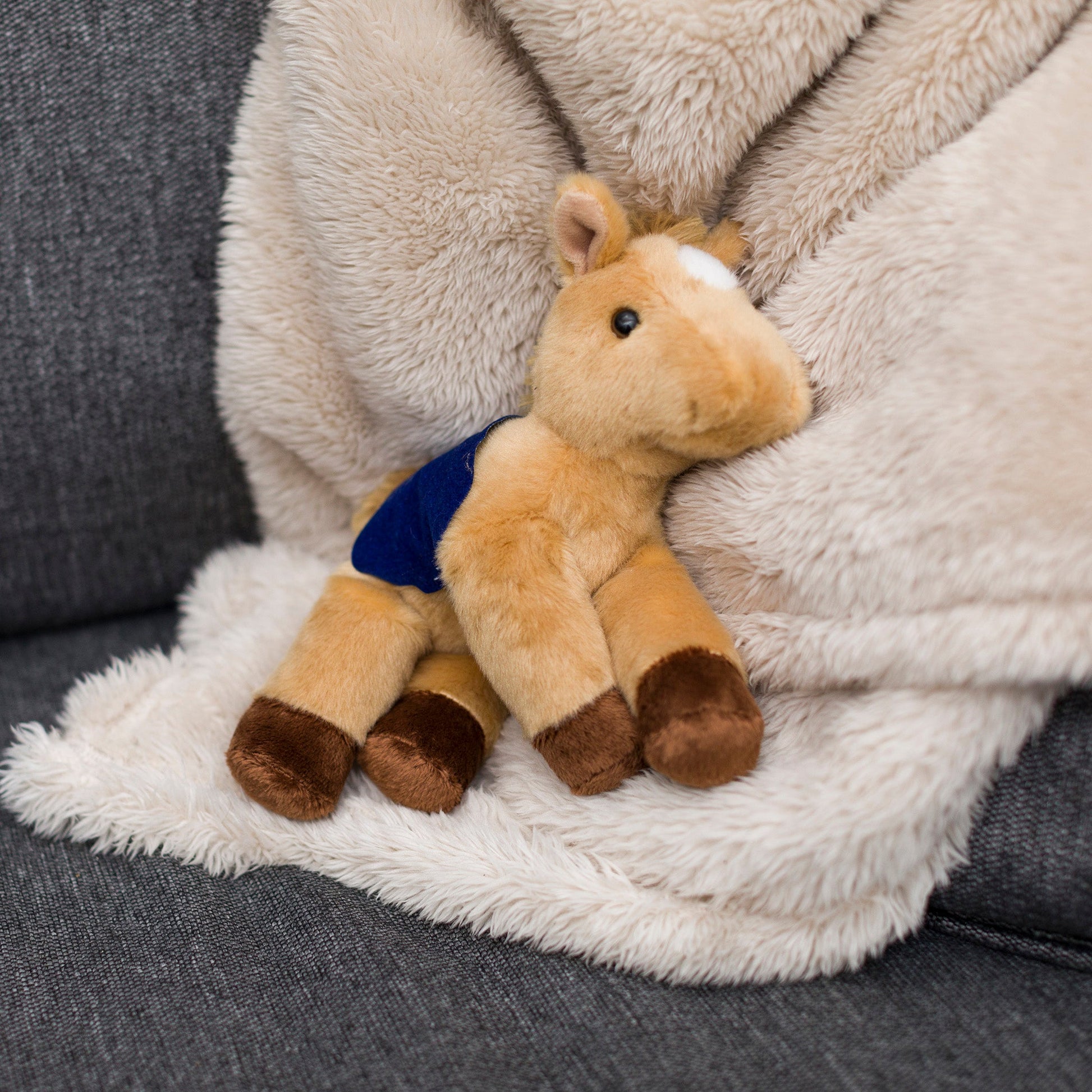 Small Prancer Horse horse stuffed animal wearing a royal blue branded mane 'n tail saddle. Standing on a blanket