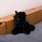 Small Scottish Terrier stuffed animal wearing a royal blue branded mane 'n tail bandana. Standing on a cushion.