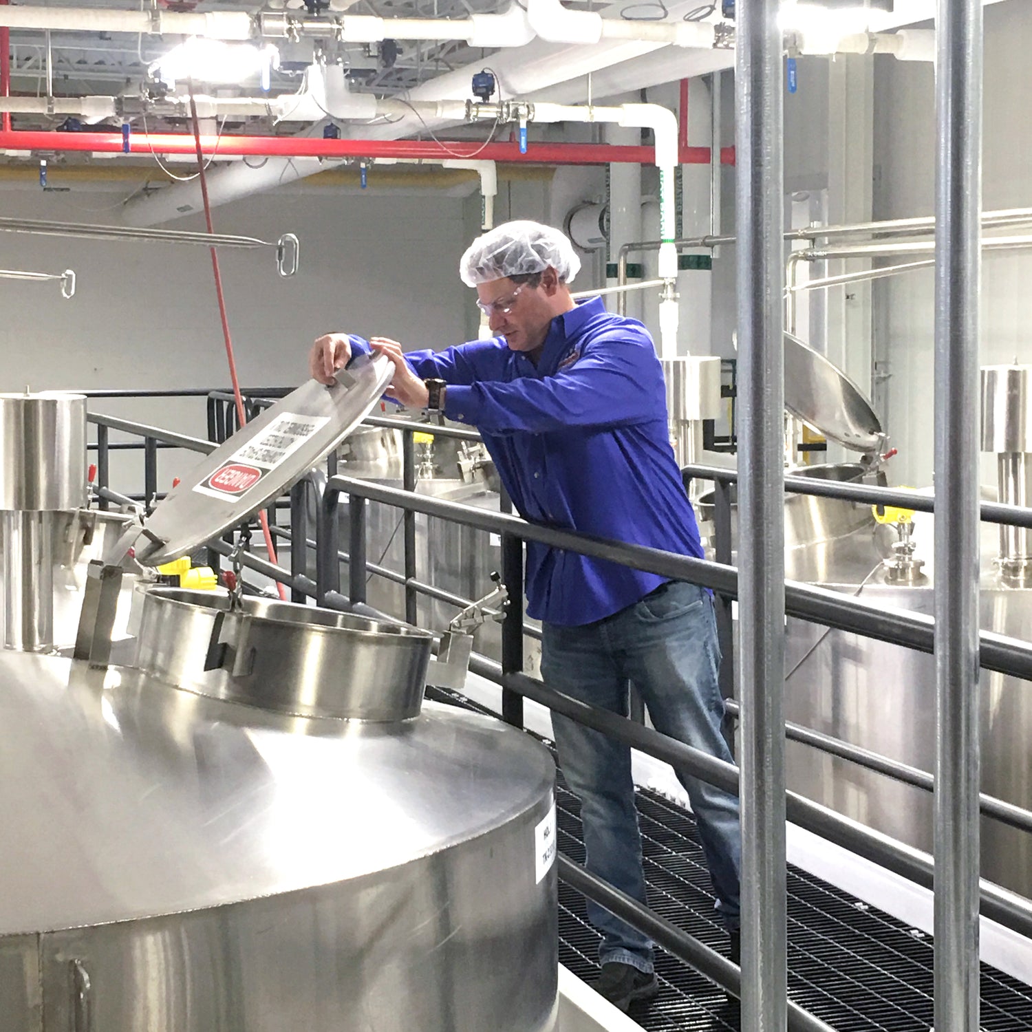 Devon looking into a large vat of on a catwalk