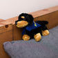 Small Vienna Dachshund stuffed animal wearing a royal blue branded mane 'n tail bandana. Sitting on a cushion
